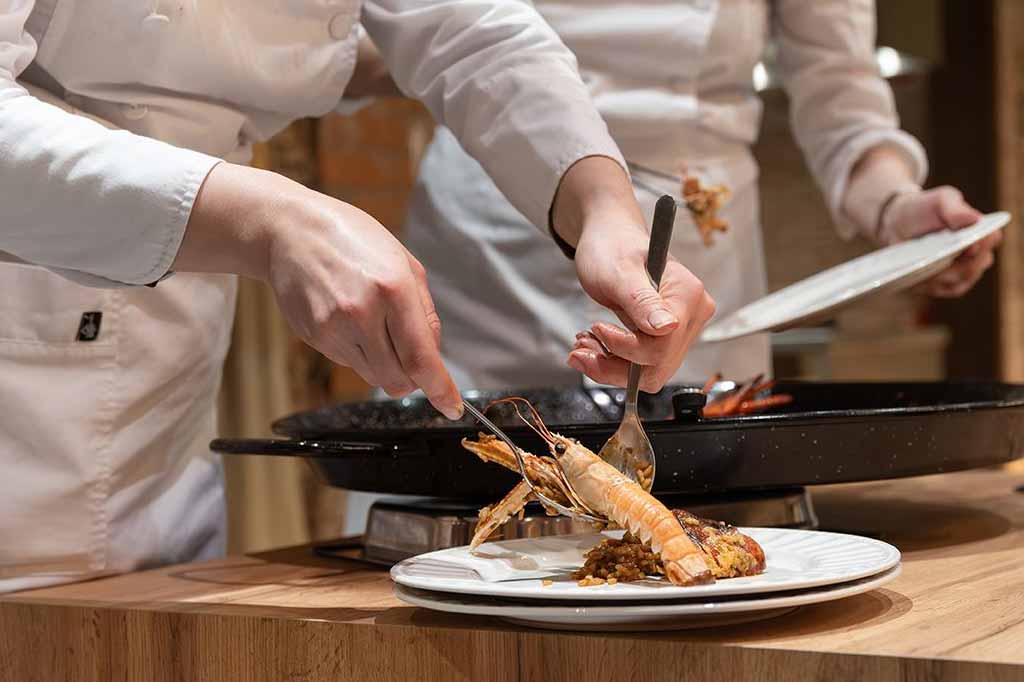 Chef profesional enseñando el punto del arroz y el socarrat en una clase de paella en Barcelona