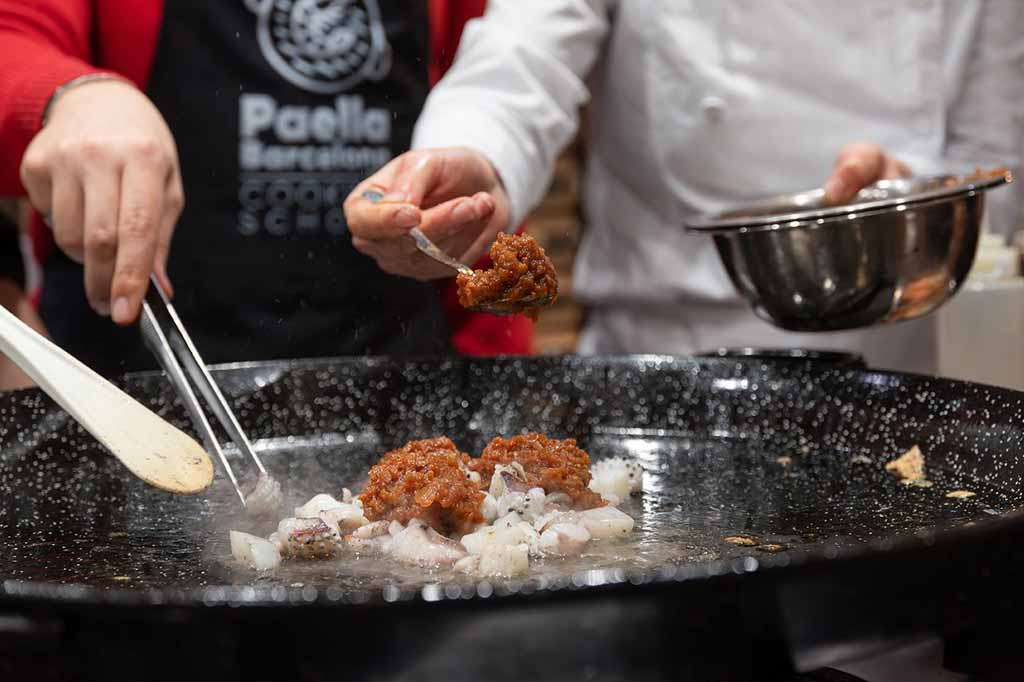 Familia con niños aprendiendo a cocinar paella en un taller de cocina en Barcelona
