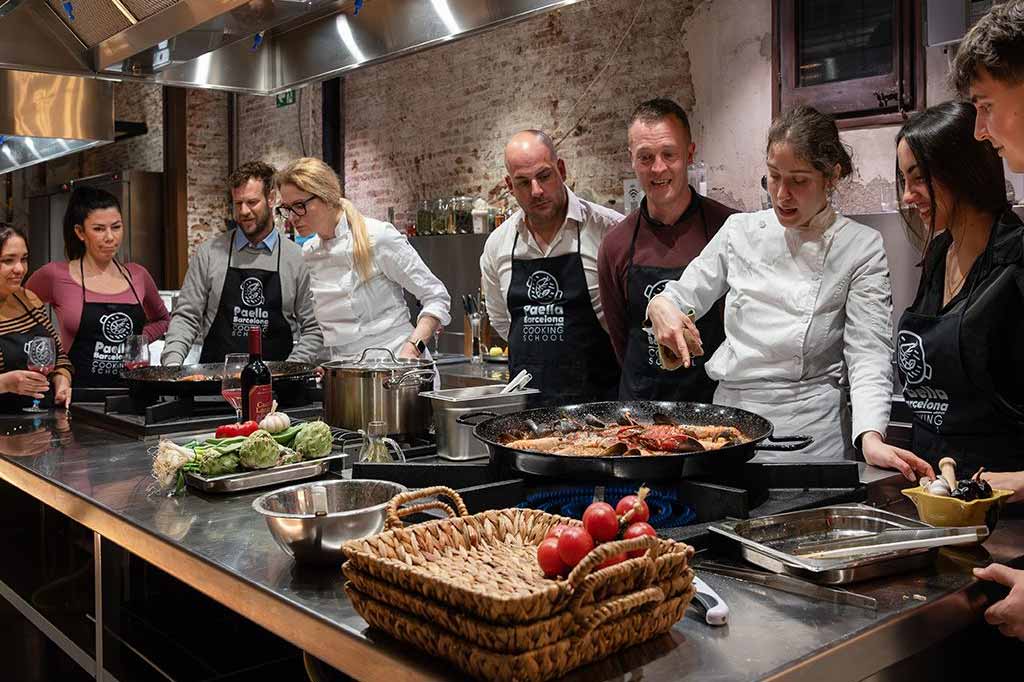Grupo de amigos cocinando una paella en una clase de cocina en el centro de Barcelona