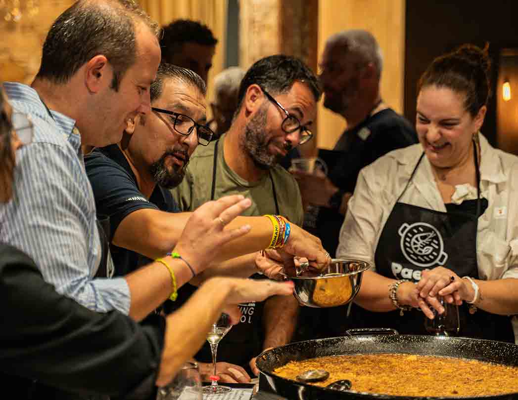 Foto de un taller de paella para empresas en Barcelona donde el equipo cocina junto y colabora en pasos interconectados. Actividad de team building culinario con responsabilidades definidas, participación de todos y enfoque en cohesión, comunicación y éxito colectivo.