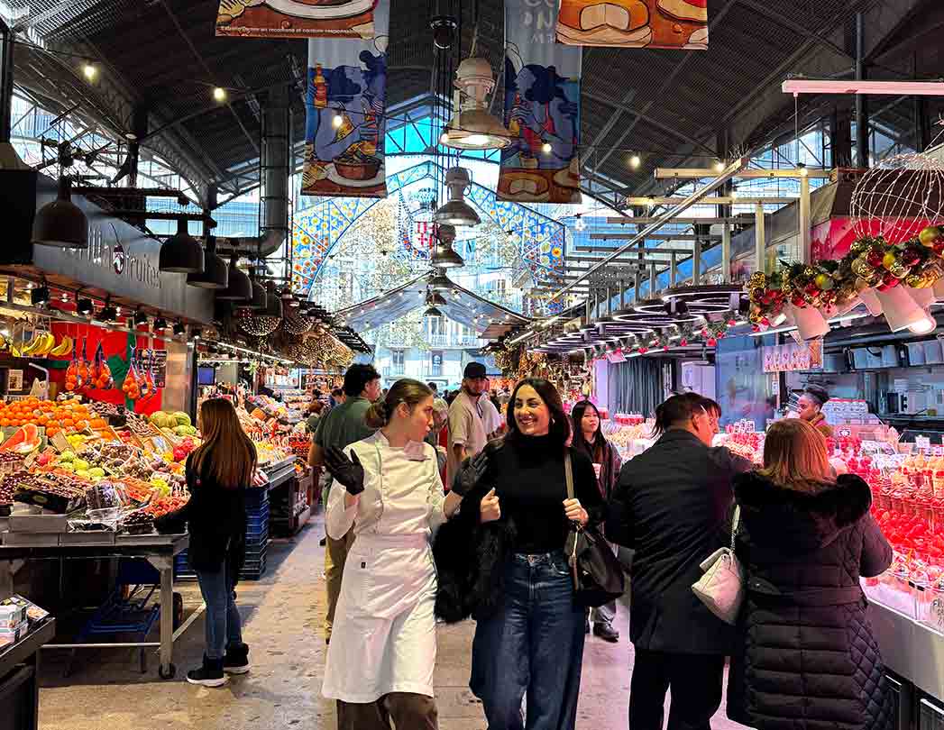 Foto del Mercado de La Boqueria en Barcelona durante el inicio del team building culinario: el grupo realiza un desafío de compras con presupuesto para seleccionar ingredientes frescos antes del taller de paella. Experiencia auténtica para empresas que fomenta colaboración, negociación y toma de decisiones.